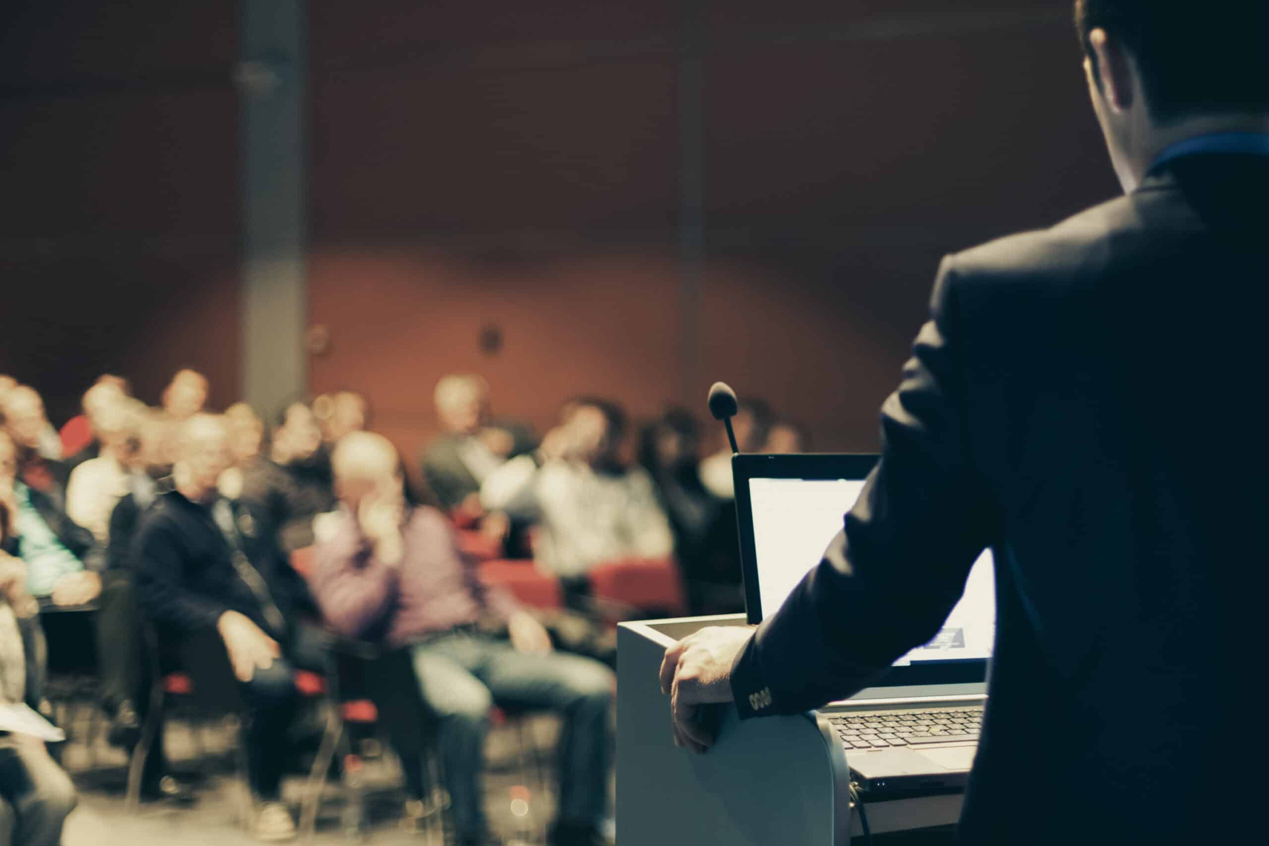 Business professional delivering a presentation to an audience in a conference room.