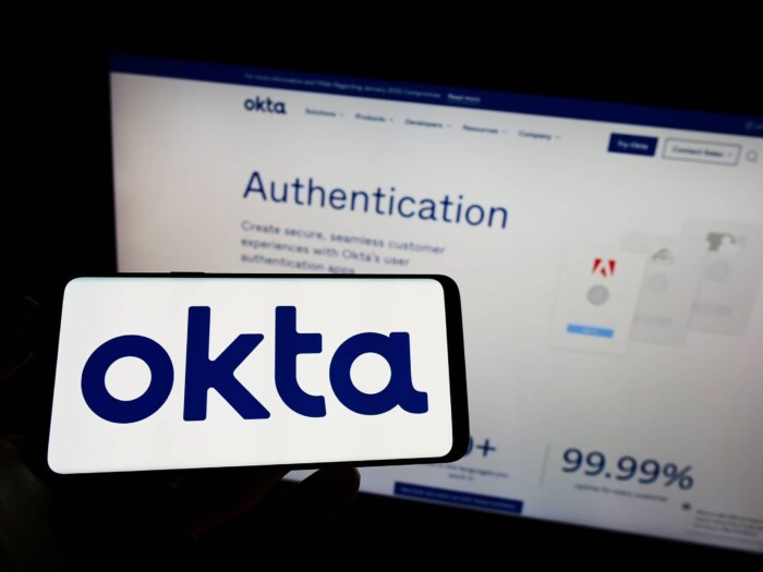 Okta logo in front of Okta authentication webpage on a computer screen.