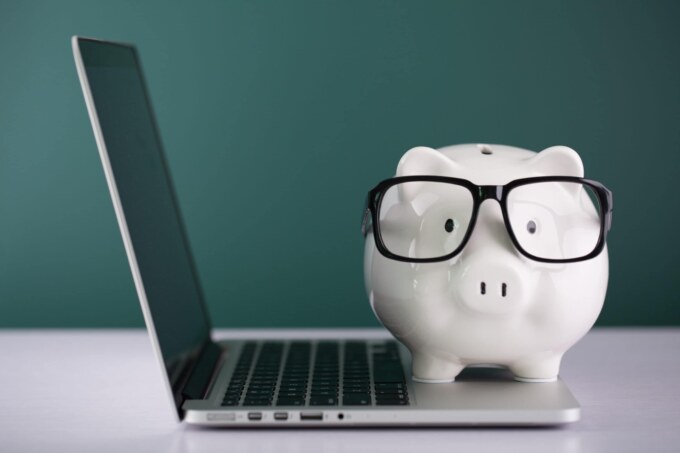 Piggy bank with glasses on a laptop, symbolizing budgeting for IT consulting services.