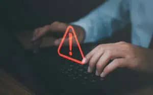 Person typing on laptop with SharePoint error alert icon overlay.