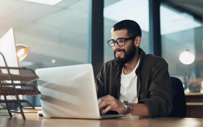 Business professional working on a laptop to overcome software scalability challenges.