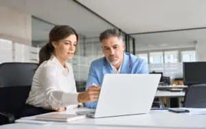 Business professionals using cloud-based access control system on laptop.