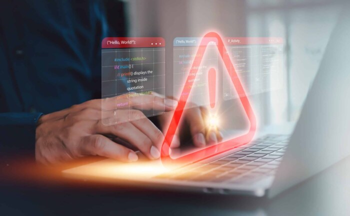 Business IT systems analysis alert with warning icon on laptop screen.