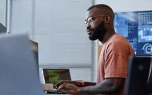 Business professional analyzing IT systems on computer screen in modern office.