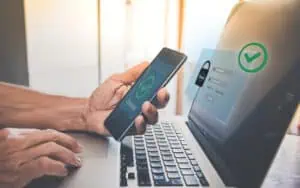 Person authenticating identity using a smartphone and laptop for secure access.