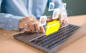 Person transferring digital files on laptop for SharePoint migration to Power Automate.