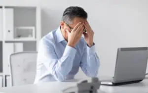 Frustrated man fixing Excel issues on his laptop at work.