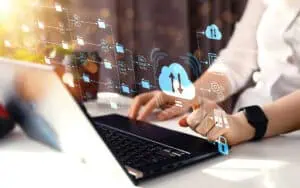 Person using a laptop with cloud and data icons representing Microsoft tools integration.