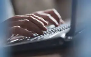 Hands typing on a laptop keyboard emphasizing data security and compliance.