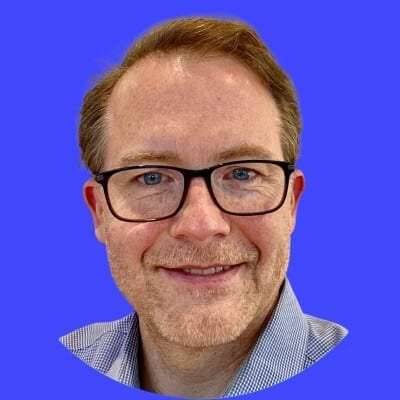Headshot of a professional man with glasses against a blue background.