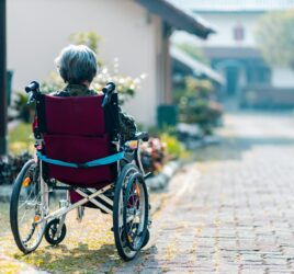 Old woman sitting in a wheelchair outside - dangers of wandering behavior in the elderly
