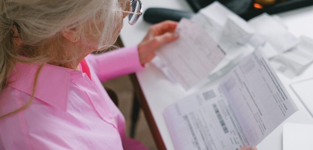 Elderly woman examines bills looking for elder financial abuse,