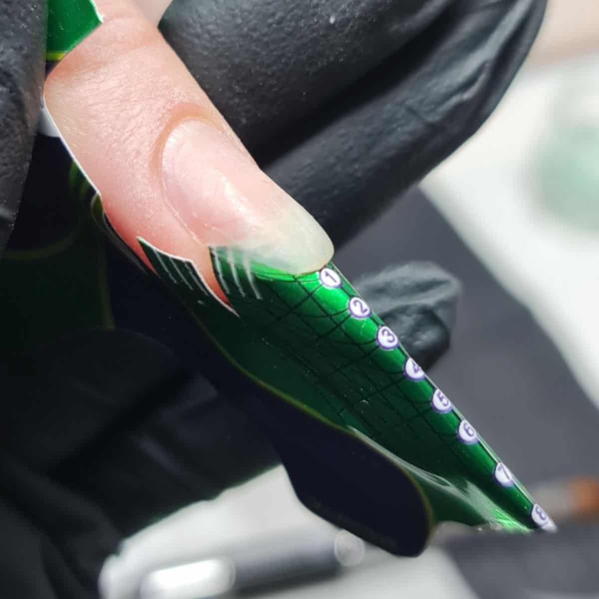 Gelnagel met nummering en groene design, professionele nagelkunst.