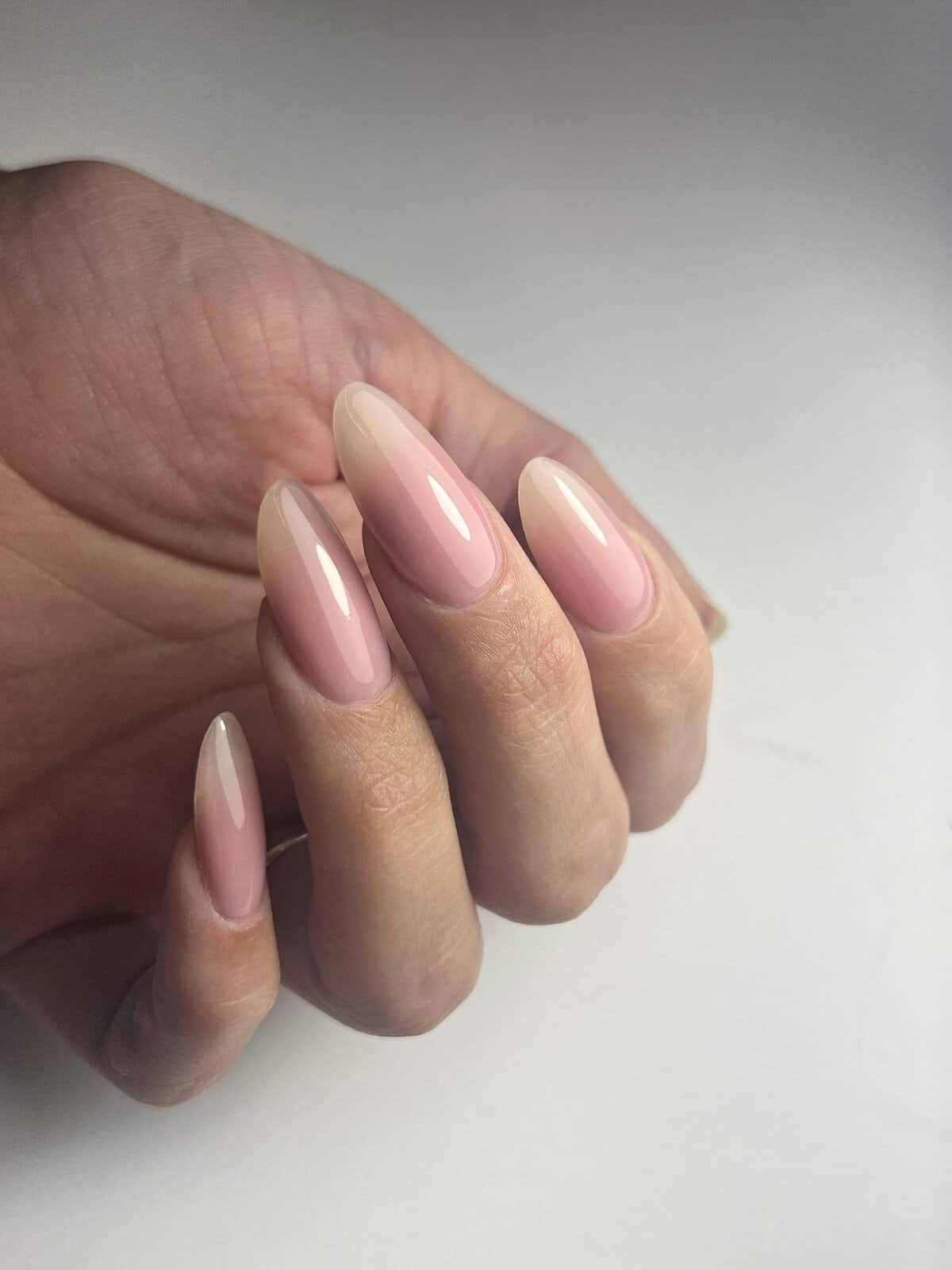 Nude gel nagels op natuurlijke hand, perfect voor een verzorgde uitstraling.
