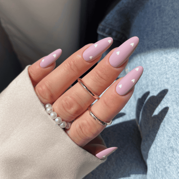 Gelnagels met zachte roze kleur en witte hartdetails, perfect voor elegante en trendy manicure.