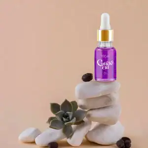 Yoshi Cuticle Oil in een glazen fles met pipet, gestapeld op witte stenen met een succulent plant.