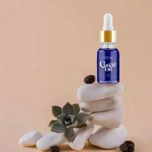 Yoshi Cuticle Oil in een blauwe fles met pipet, omringd door witte stenen en een succulent, voor gez.