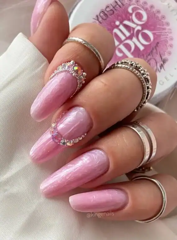 Elegante roze gelnagels met glanzende afwerking en sierlijke ringaccessoires voor een stijlvolle loo.