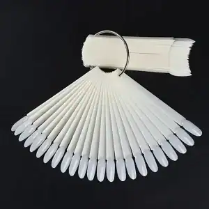 Witte nagelstalen en teststiften voor nagelkunst en nagelverzorging op zwart achtergrond.