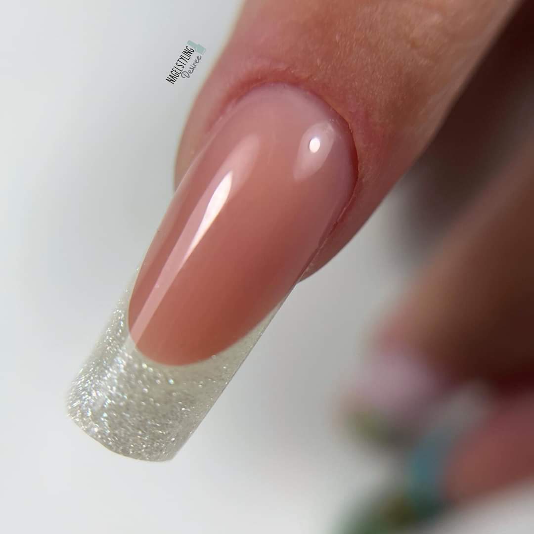 Close-up van een nagel met een Franse manicure en glitterrand.