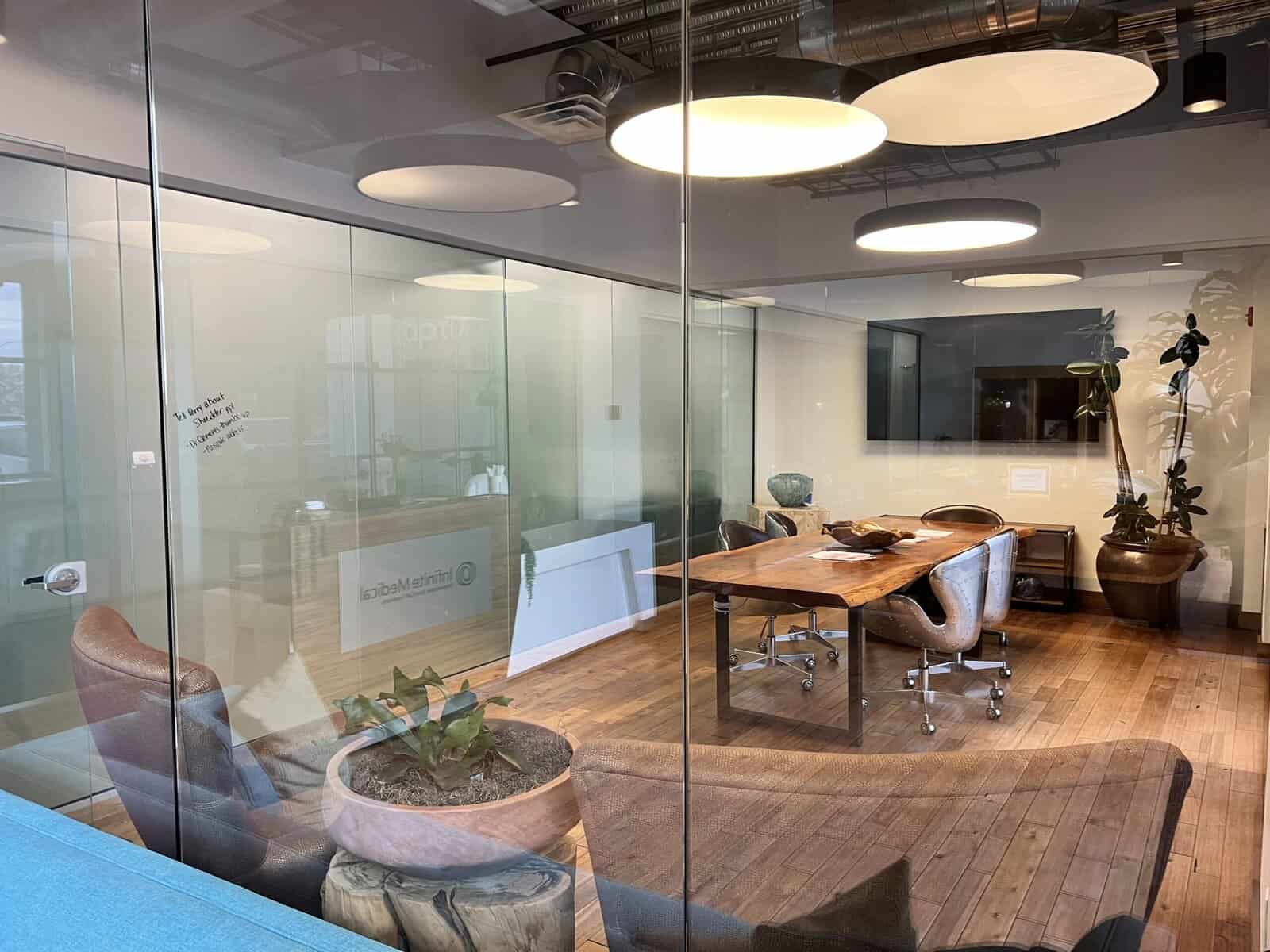 Modern conference room with wooden table, leather chairs, and decorative plants in a professional medical clinic.