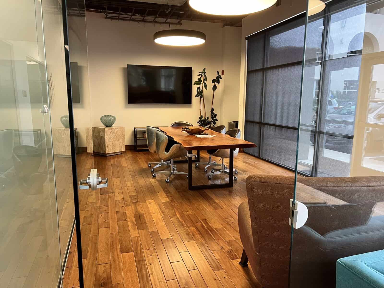 Modern conference room with large windows, wooden flooring, and sleek furniture at Infinite Medical in St. George, Utah.