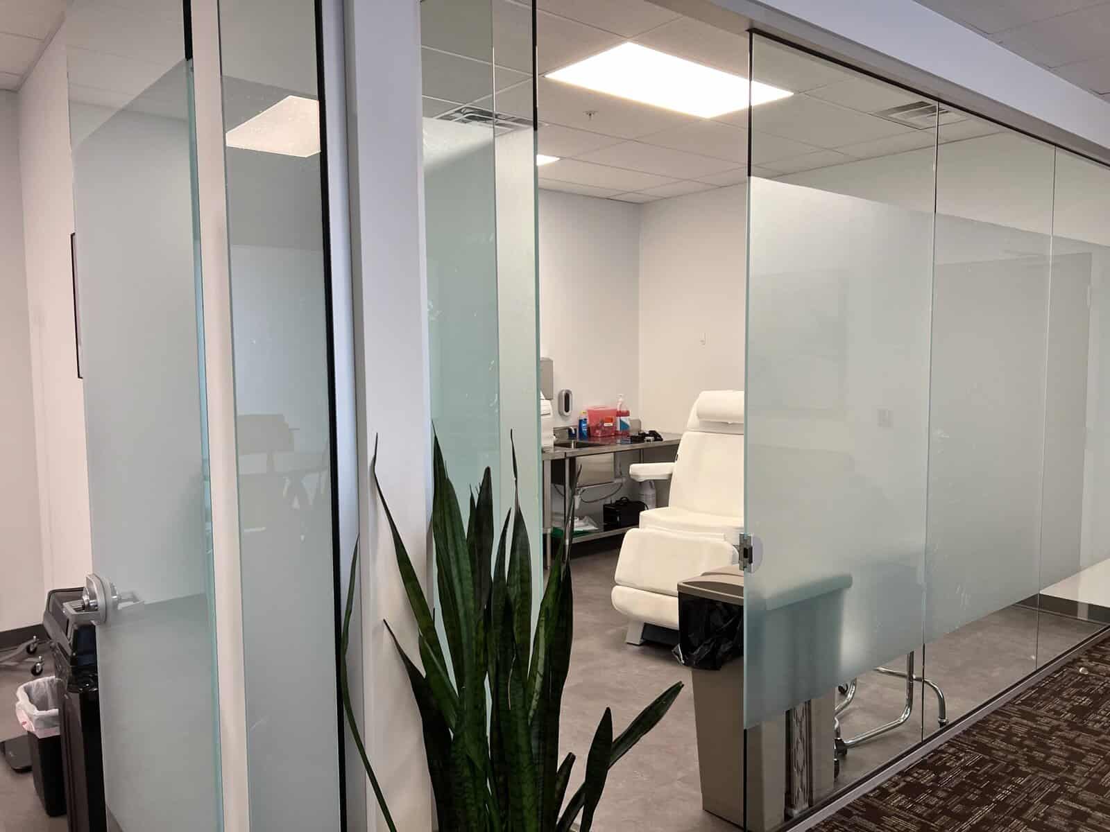 Modern medical clinic room with glass walls, examination chair, and medical supplies in Salt Lake City.