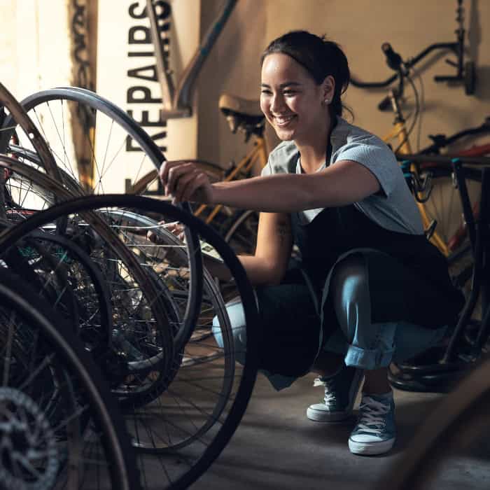 bike shop owner smiling about business insurance as she inspects tires