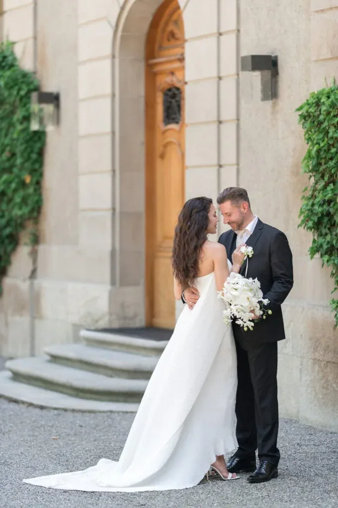 Hochzeitspaar vor altem Gebäude mit Tür und grünen Pflanzen, romantische Hochzeitsaufnahme.