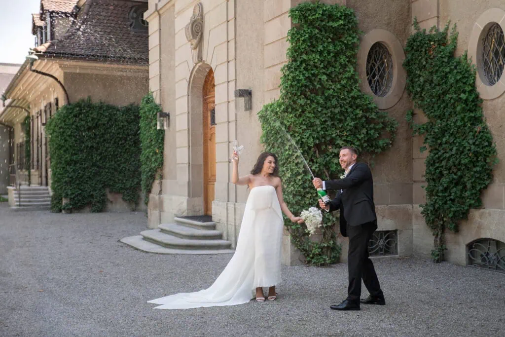 Hochzeit im Freien: Braut und Bräutigam feiern vor einer historischen Kirche.