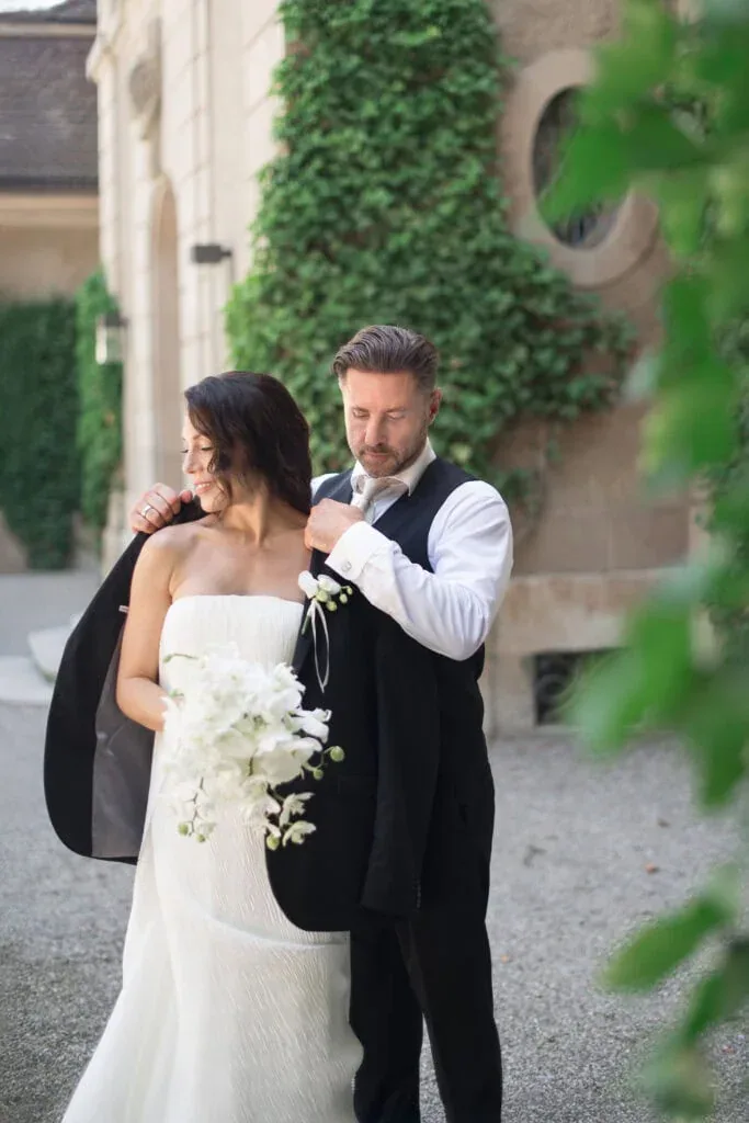 Hochzeitspaar bei der Aufnahme vor einer alten Steinmauer mit grünen Pflanzen im Hintergrund.