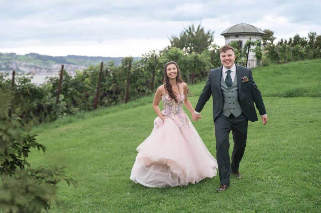 Hochzeitspaar beim Spaziergang im Grünen, lachend und glücklich, mit Natur im Hintergrund.