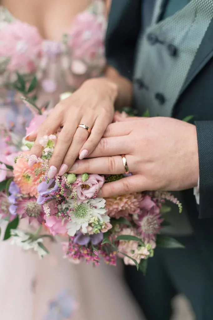 Nahaufnahme der Eheringe auf einem Blumenstrauß bei einer Hochzeit.