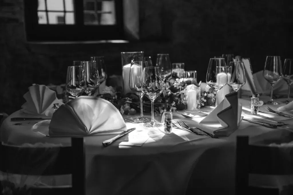 Eleganter Hochzeitstisch mit Kerzen, Gläsern und gefalteten Servietten.
