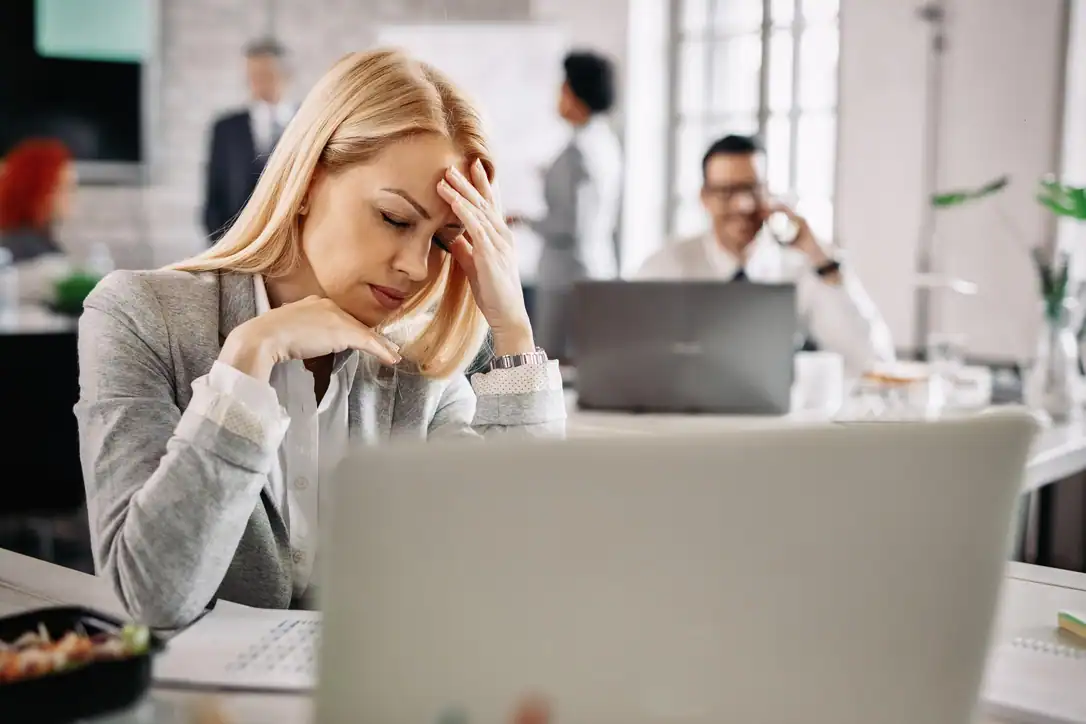 Mujer estresada en oficina durante una crisis, representando la importancia de la ISO 22301 para la continuidad del negocio.