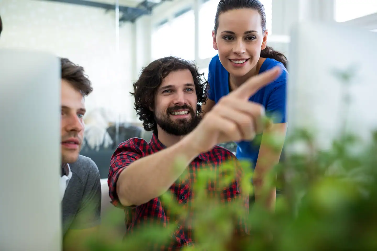 Tres profesionales colaborando en un proyecto para conseguir la certificación ISO 14001 en una oficina moderna y sostenible.