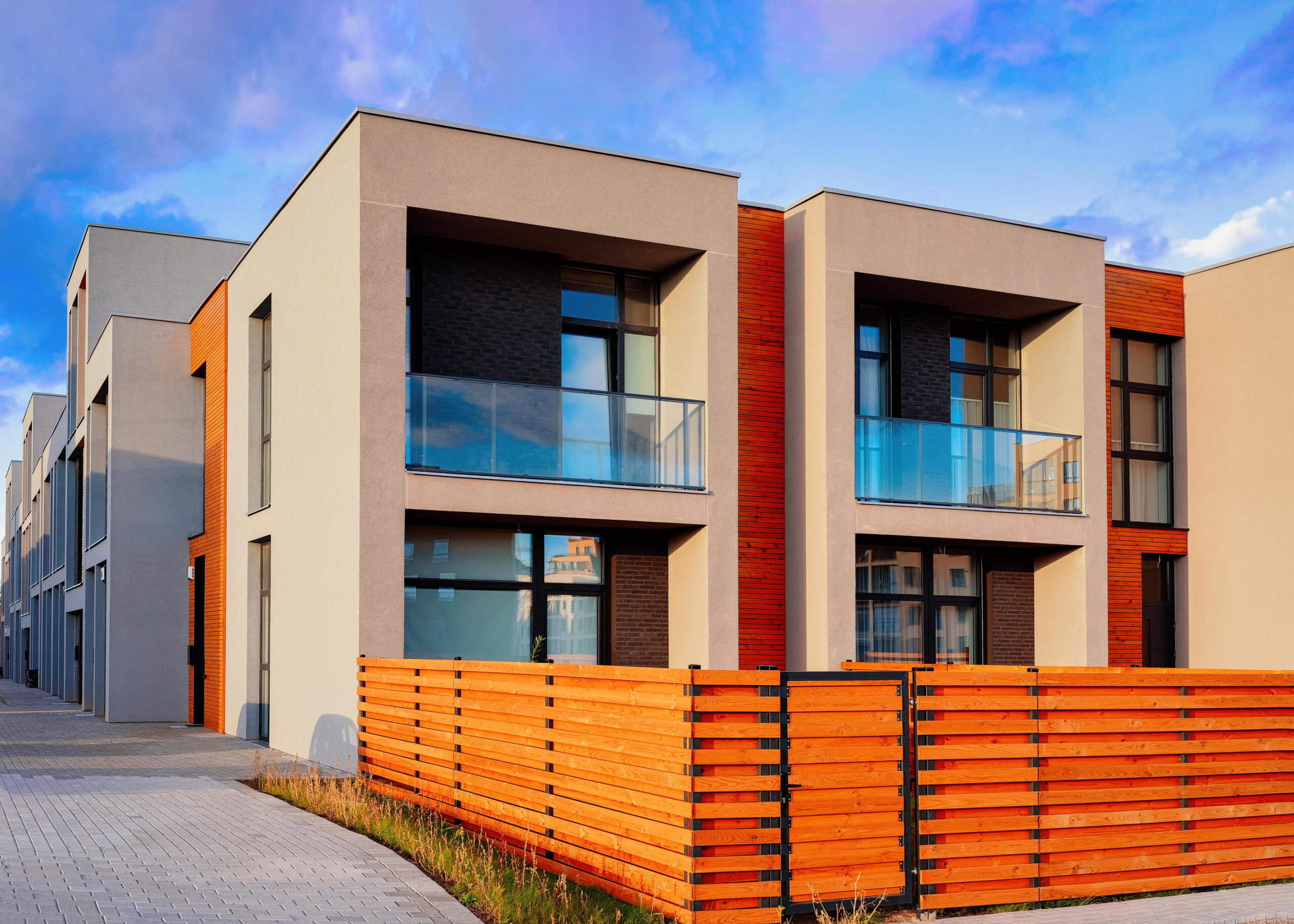 Contemporary apartment building with balconies and wooden fencing.