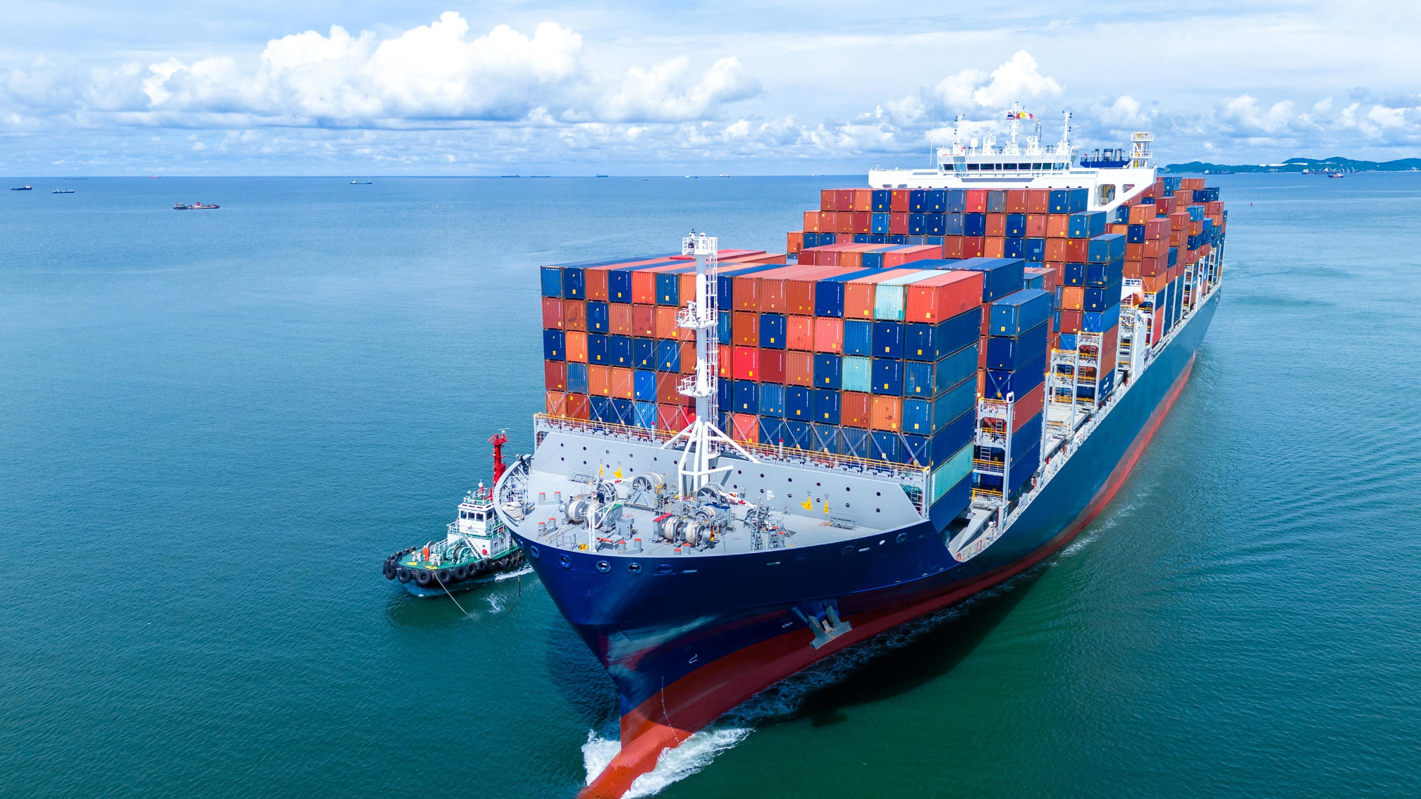 Large cargo ship carrying containers on open sea for insurance coverage.