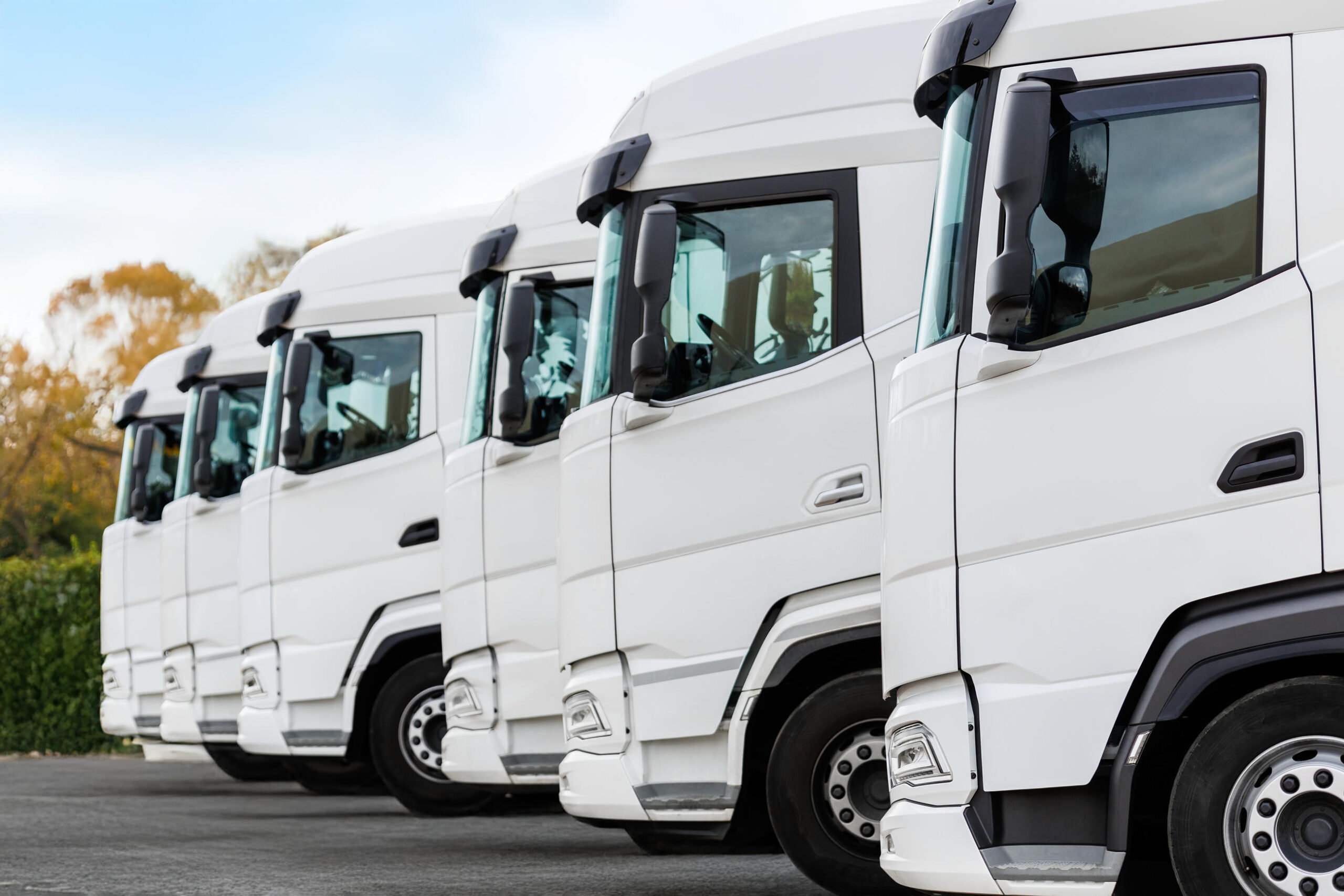 Line of white trucks parked outdoors for insurance coverage.