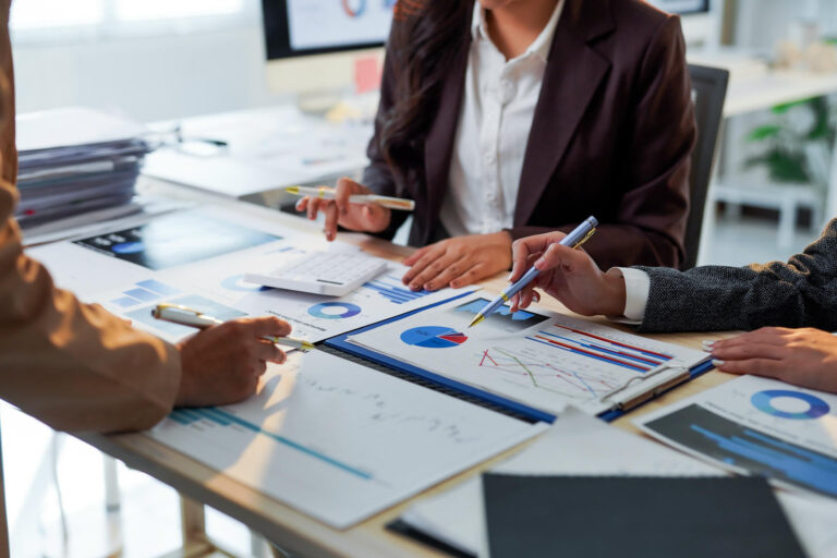 Business professionals reviewing insurance documents and charts at a meeting table.