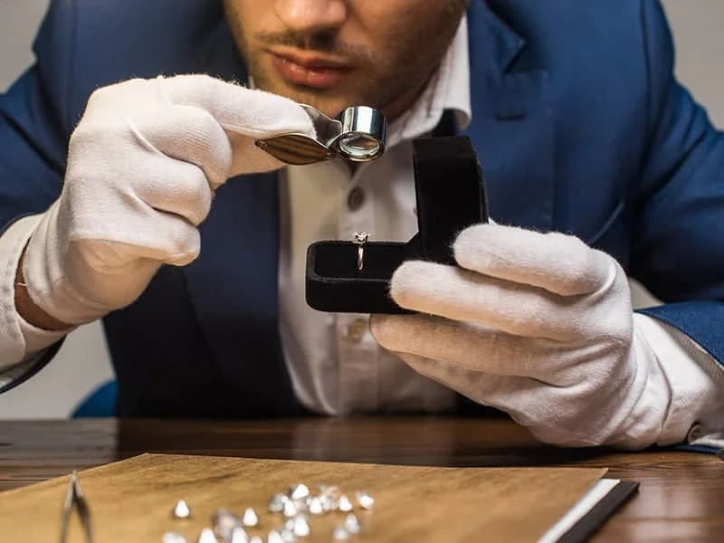 Shining engagement ring being examined with magnifying glass in Calgary jewelry shop.