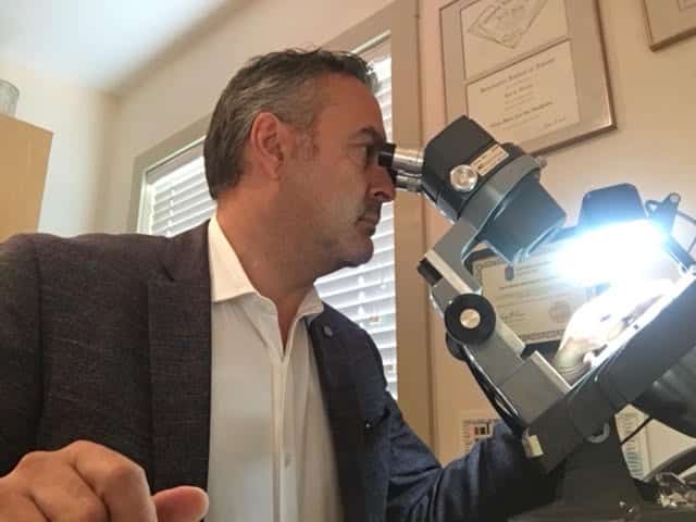 Calgary jewelry expert examining gemstones under microscope.