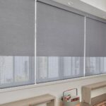 Smooth, gray roller blackout shades on large windows, providing privacy and light control in a stylish room.