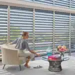 Bright contemporary living room featuring large horizontal blinds, cozy sofa, and elegant decor elements for relaxed living spaces.