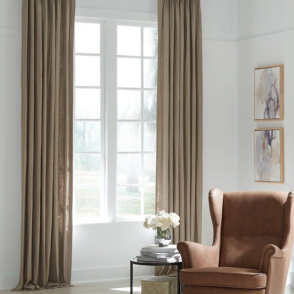 Luxurious beige drapes frame a bright window, adding a cozy touch to a modern living space with tasteful decor.