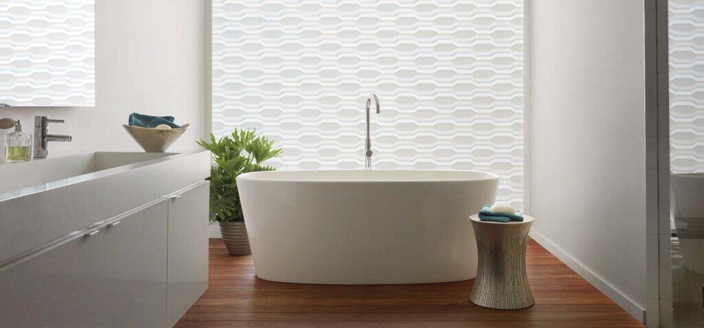 Luxurious white bathtub in contemporary bathroom featuring textured wall, wooden floor, and elegant decor.