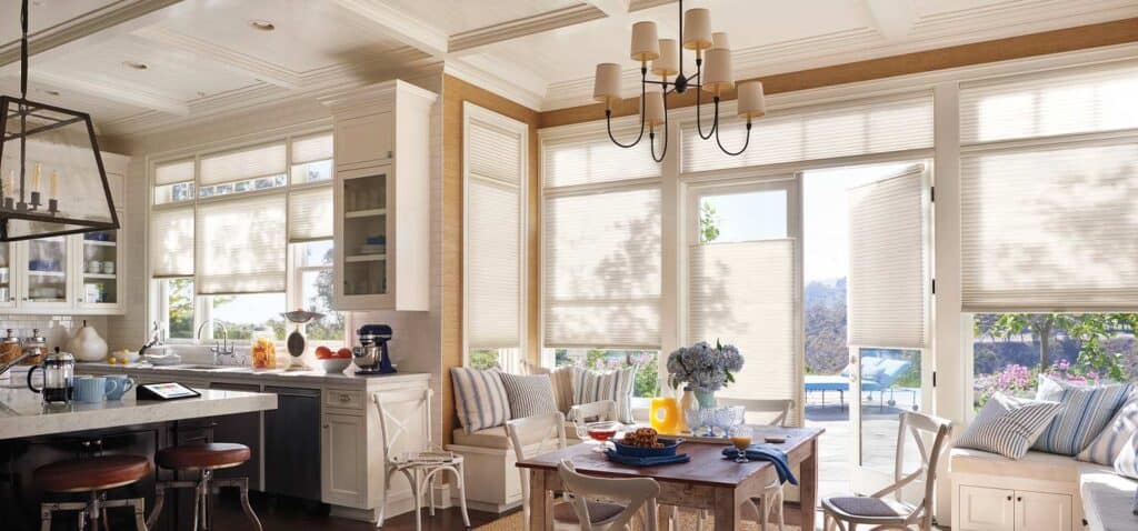 Bright kitchen with large windows, cozy dining area, and elegant decor emphasizing natural light and comfort.