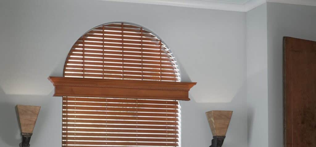 Bright arched window with wooden blinds, adding warmth and elegance to living room decor. Natural light streams through the horizontal slats, creating a welcoming and stylish home environment.