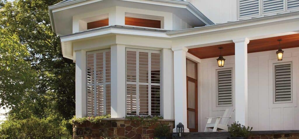 Inviting porch featuring white shutters and warm lighting for outdoor relaxation.