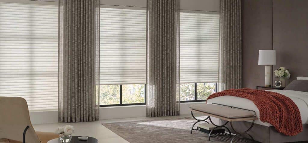 Bright contemporary bedroom with large windows, white blinds, and soft furnishings, creating a calming and stylish space.